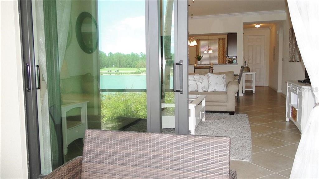 A view from a patio through sliding glass doors into a living room and kitchen — 16804 VARDON TERRACE UNIT 105, BRADENTON, FL