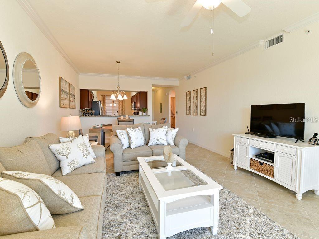 A living room with a beige sofa, a white coffee table, and a television console — 16804 VARDON TERRACE UNIT 105, BRADENTON, FL