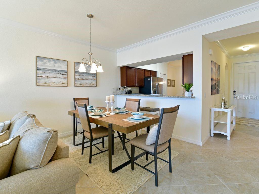 A dining area with a wooden table and chairs sits adjacent to a kitchen counter — 16804 VARDON TERRACE UNIT 105, BRADENTON, FL