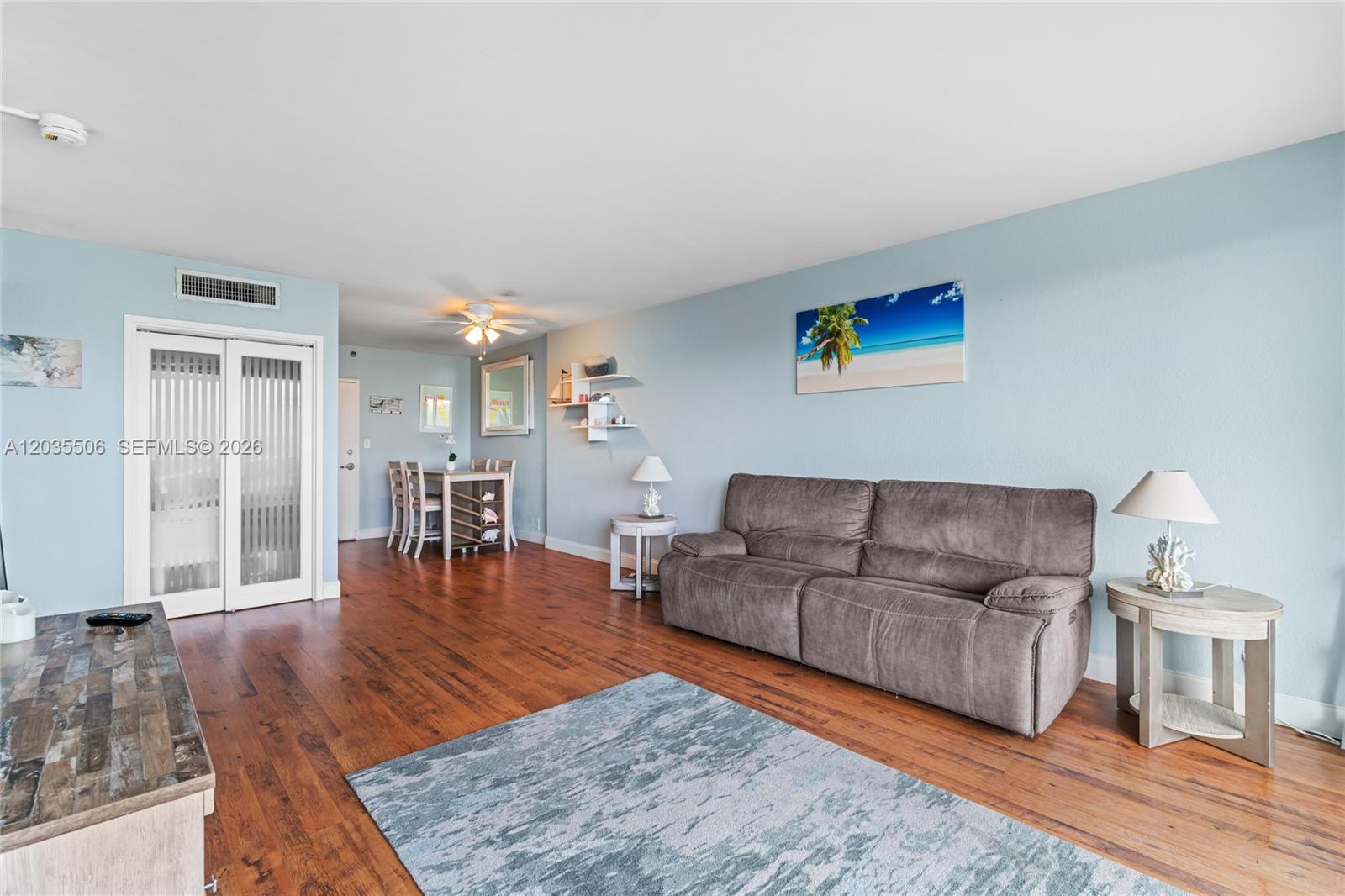 A living room features light blue walls, hardwood floors, a gray sofa, and a dining area — 1000 West Ave # 308, Miami Beach FL 33139, MIAMI BEACH, FL