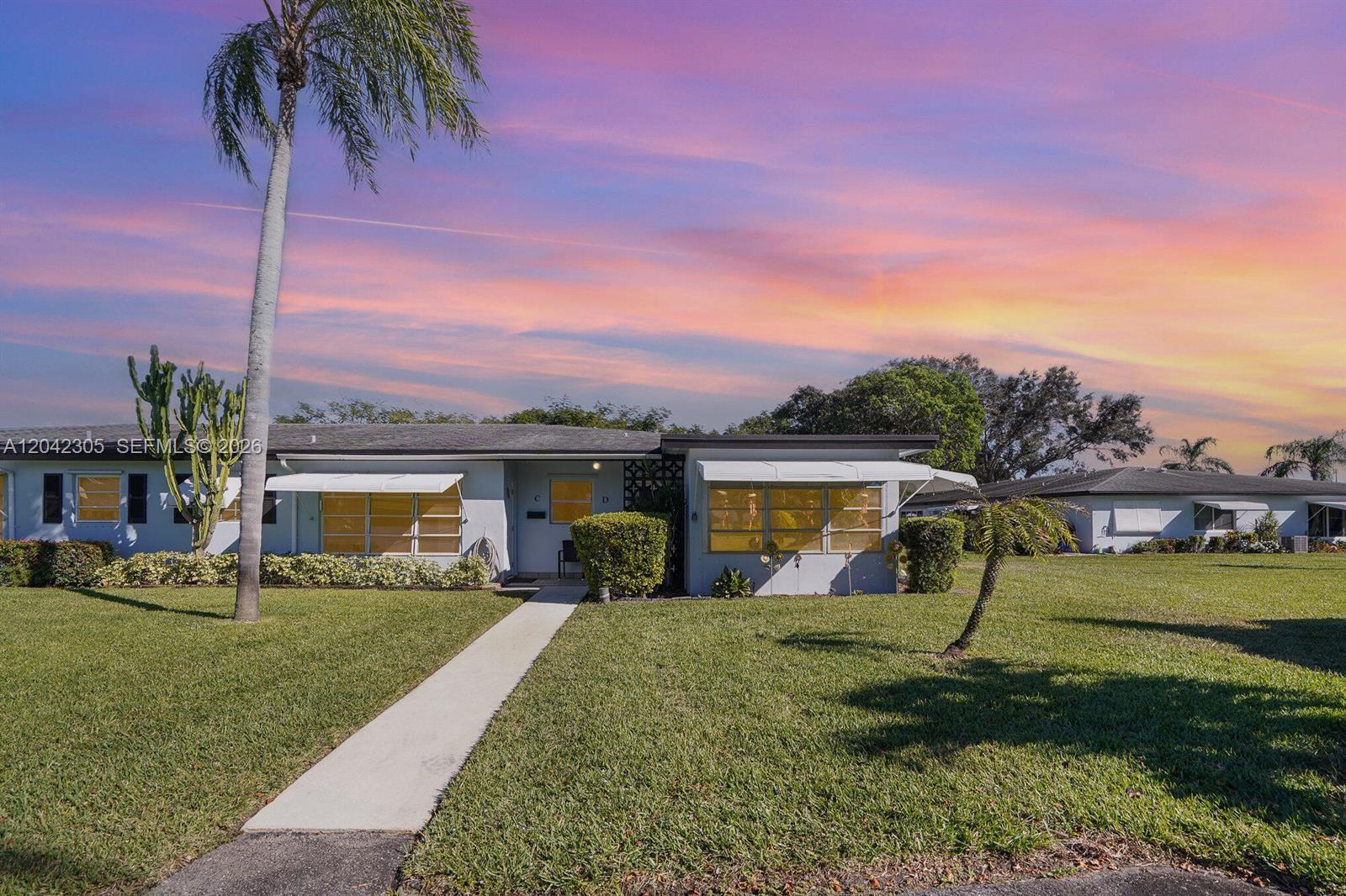 A single-story house with a light-colored exterior, white awnings, and a palm tree in front — 560 High Point Dr # D, Delray Beach FL 33445, DELRAY BEACH, FL