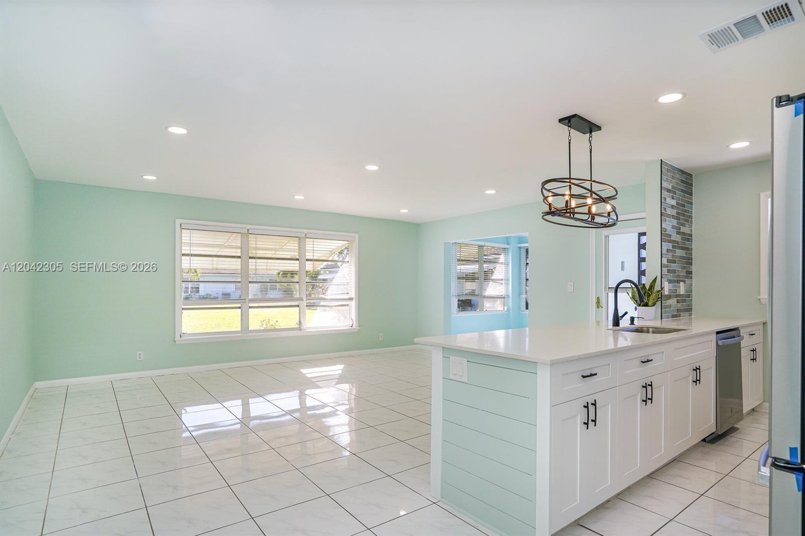 A kitchen with a white island and light green walls opens into a living area — 560 High Point Dr # D, Delray Beach FL 33445, DELRAY BEACH, FL