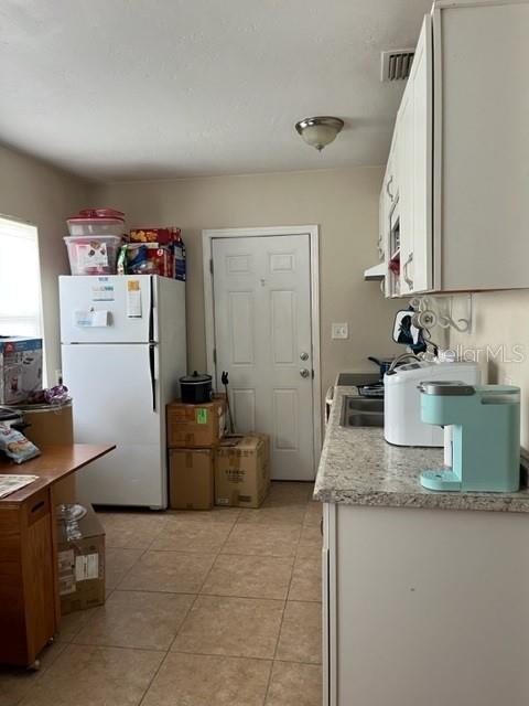 A kitchen features white cabinets, a refrigerator, a light blue coffee maker, and tile flooring — 5210 13TH AVENUE S, GULFPORT, FL