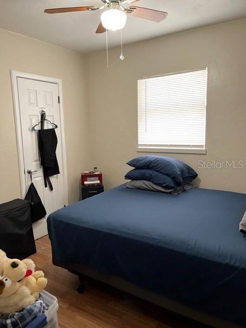 A bedroom features a bed with blue bedding, a ceiling fan, and a window with blinds — 5210 13TH AVENUE S, GULFPORT, FL
