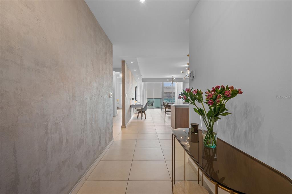 A hallway with a textured gray wall leads toward an open-concept kitchen and living area — 25 MUNOZ RIVERA UNIT 902, SAN JUAN, PR