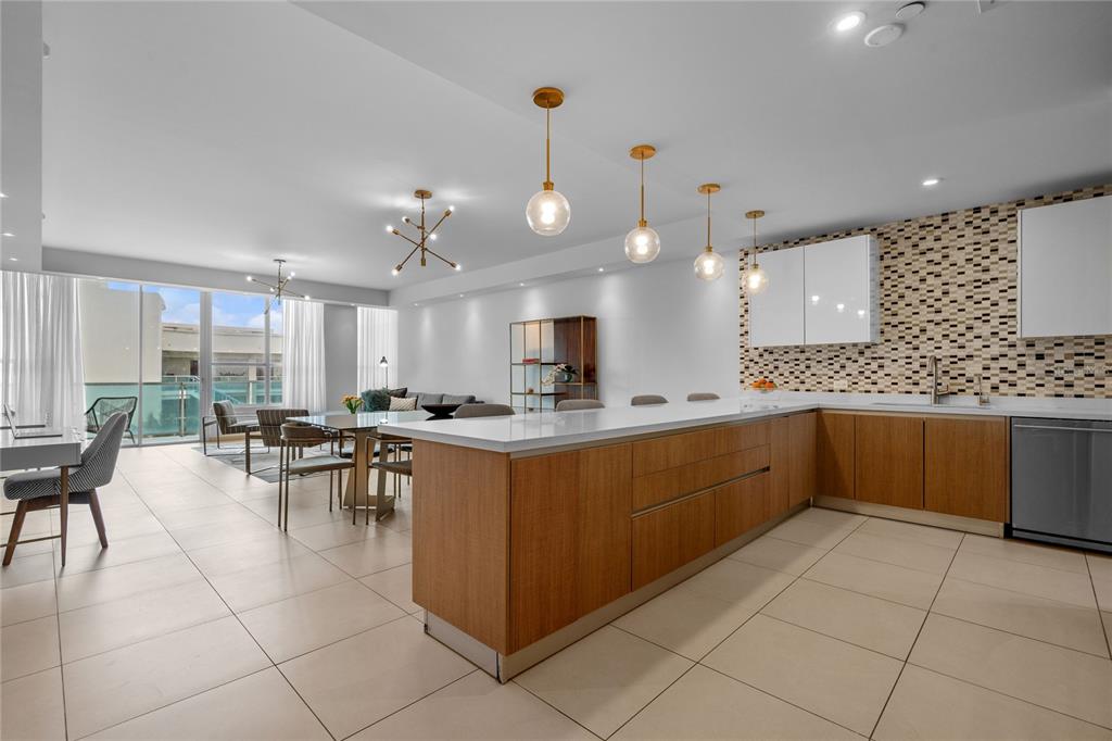 A modern kitchen with wood cabinets and a white island opens to a dining area — 25 MUNOZ RIVERA UNIT 902, SAN JUAN, PR