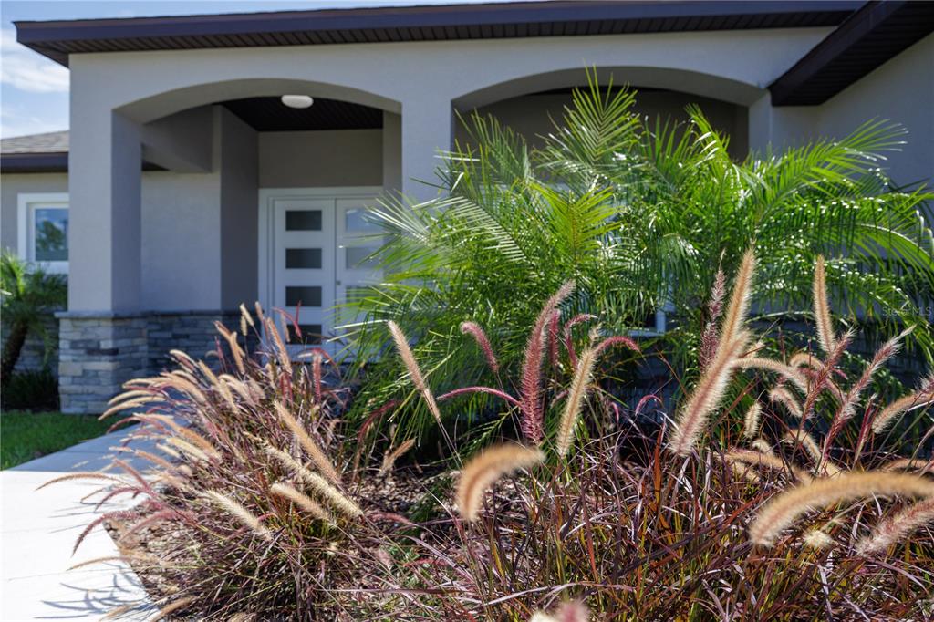 A modern house exterior features a covered entryway with arched openings and a double door — 10 RAINER PLACE, PALM COAST, FL