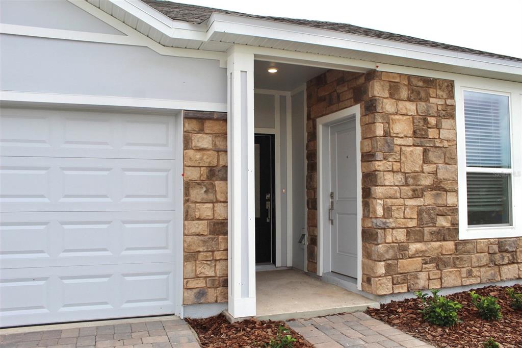 The exterior of a house features a garage, a stone facade, and a covered entryway — 4359 VIBERNUM AVENUE, ST CLOUD, FL