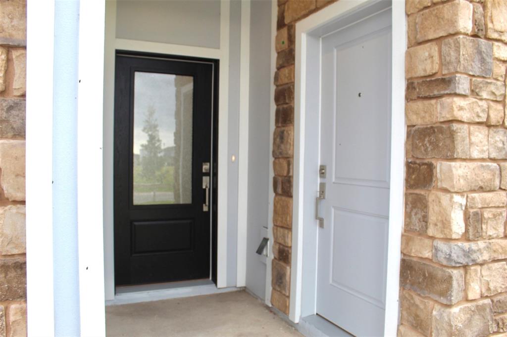 A stone-accented entryway features a black glass-paneled door next to a solid light-colored door — 4359 VIBERNUM AVENUE, ST CLOUD, FL