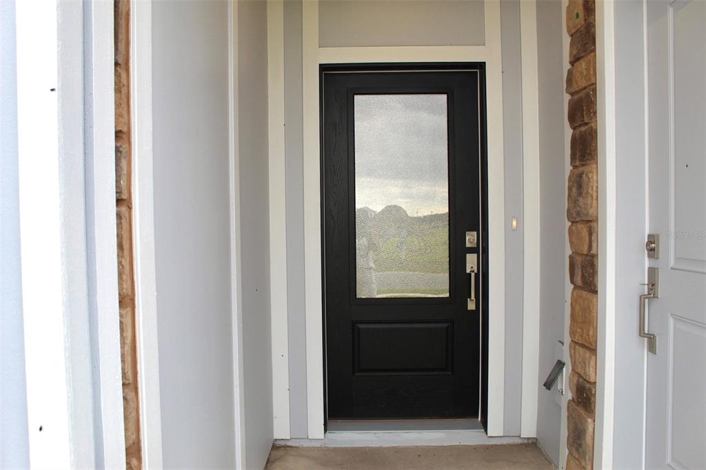 A black front door with a glass panel is set between stone-accented walls — 4359 VIBERNUM AVENUE, ST CLOUD, FL