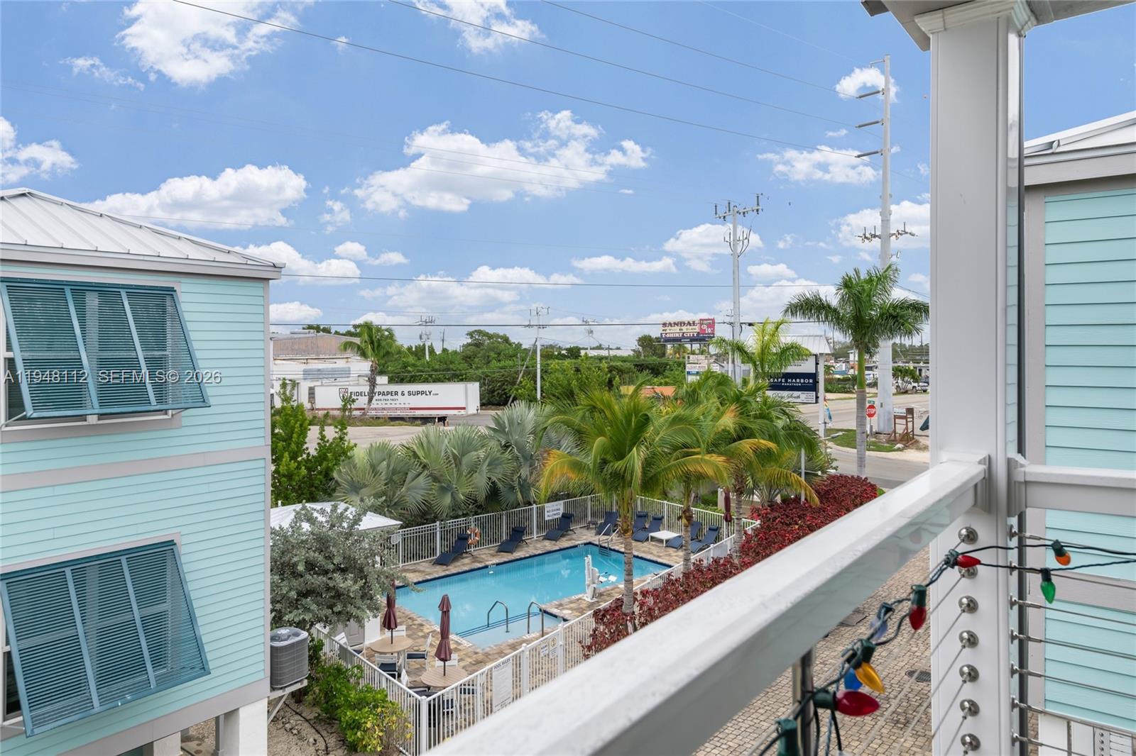 An elevated view shows a swimming pool between two light blue buildings with a parking lot — 101 11th Street Ocean, Unit 17, Marathon FL 33050, MARATHON, FL