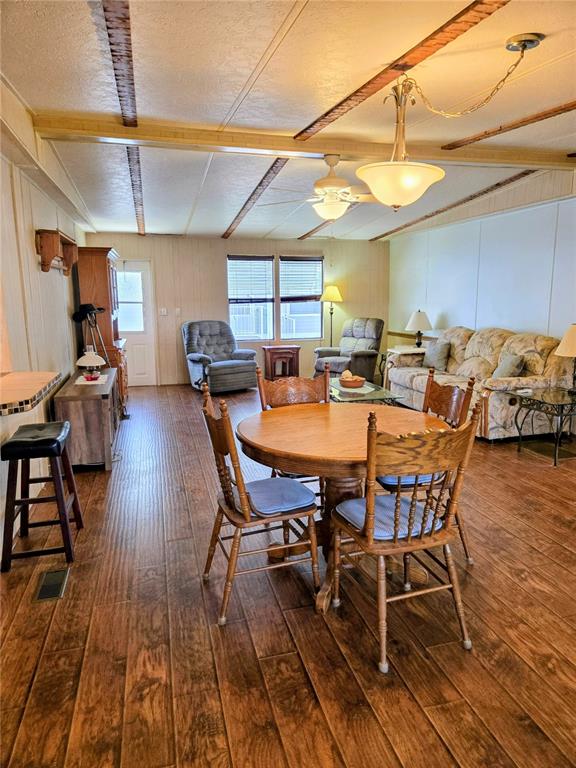 A dining area and living room feature wood-look flooring, a round table, and ceiling lights — 6253 BALMY LANE, ZEPHYRHILLS, FL