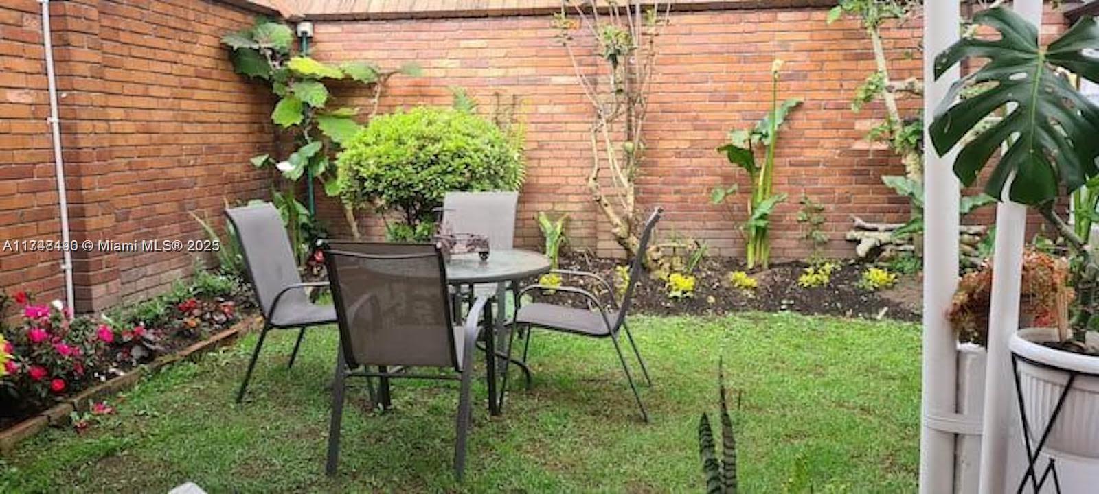 A small backyard patio features a round table with four chairs against a brick wall — cra 71 PONTEVEDRA, C 111121, C