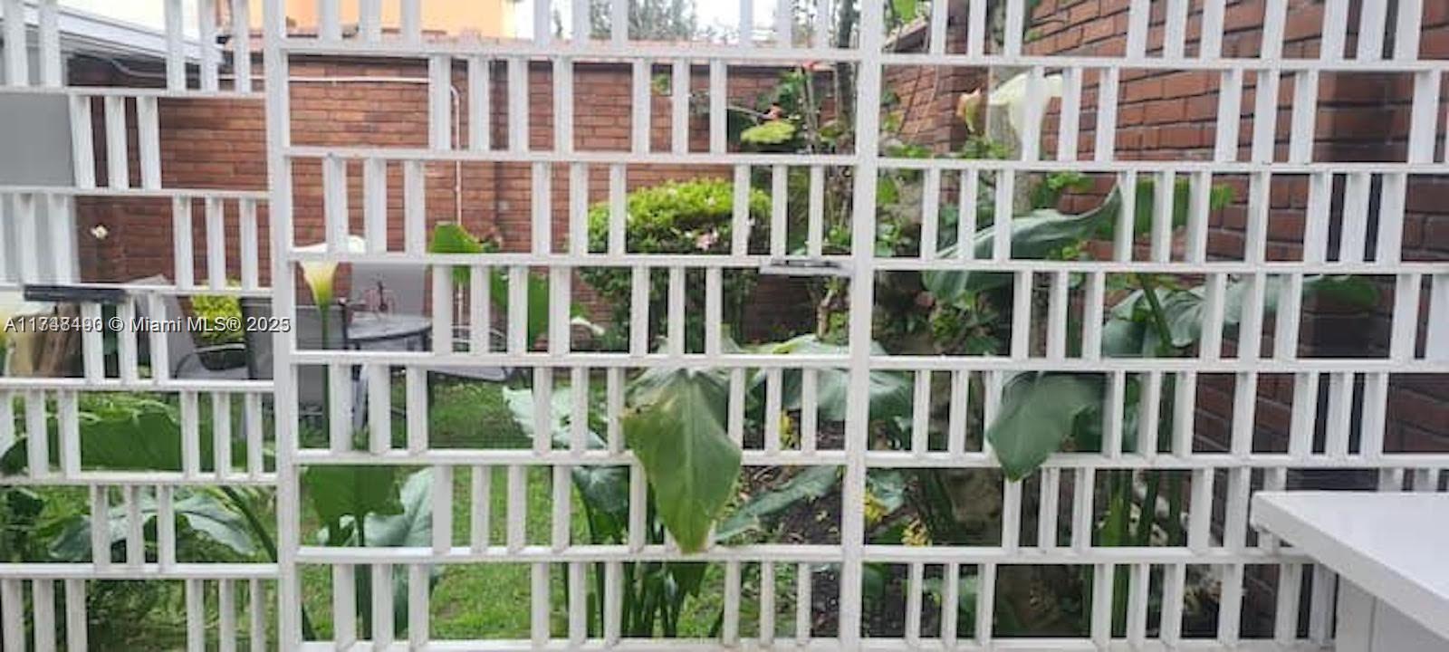 A white lattice privacy screen stands in front of a brick wall and garden area — cra 71 PONTEVEDRA, C 111121, C