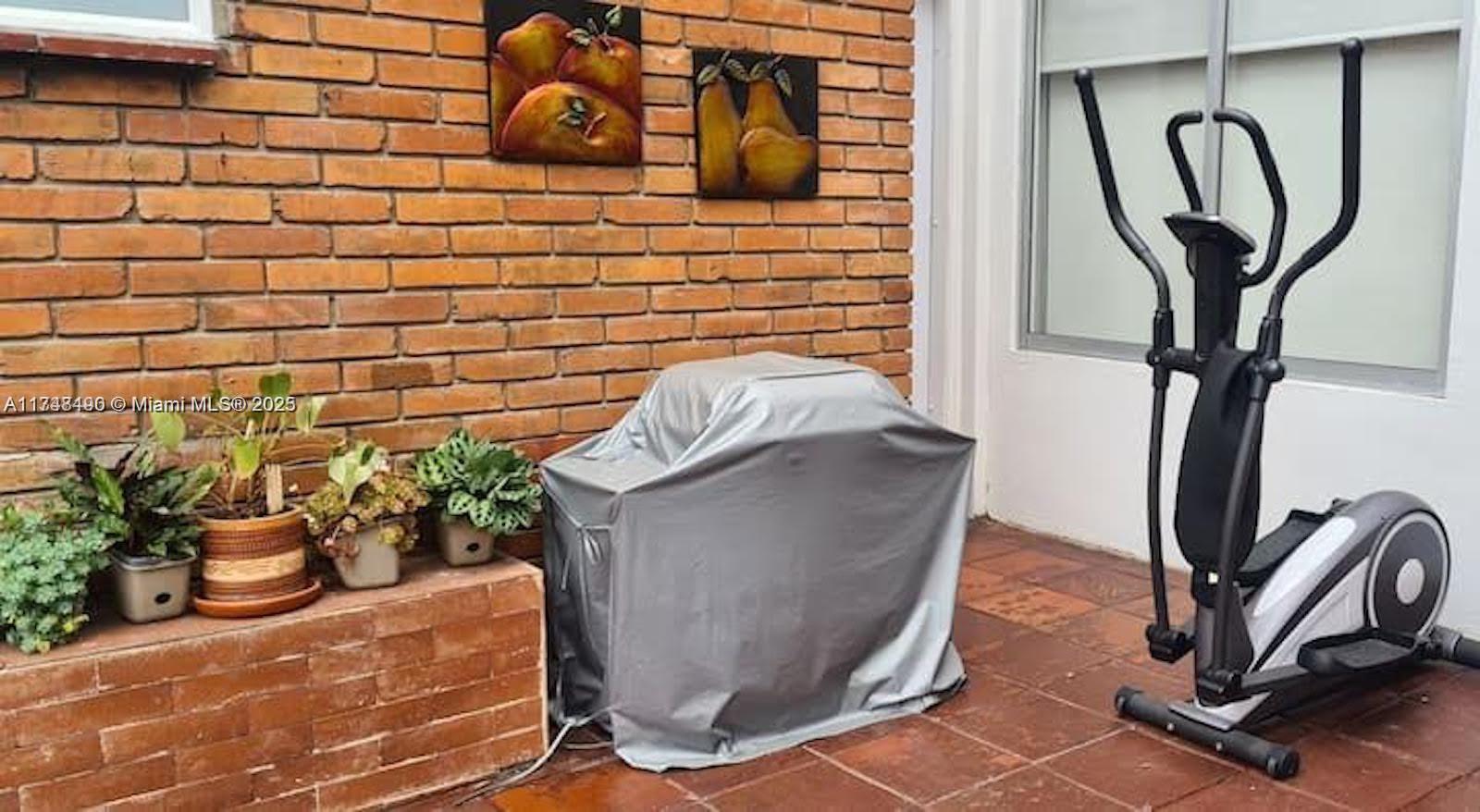 An outdoor patio features a brick wall, potted plants, a covered grill, and an elliptical machine — cra 71 PONTEVEDRA, C 111121, C