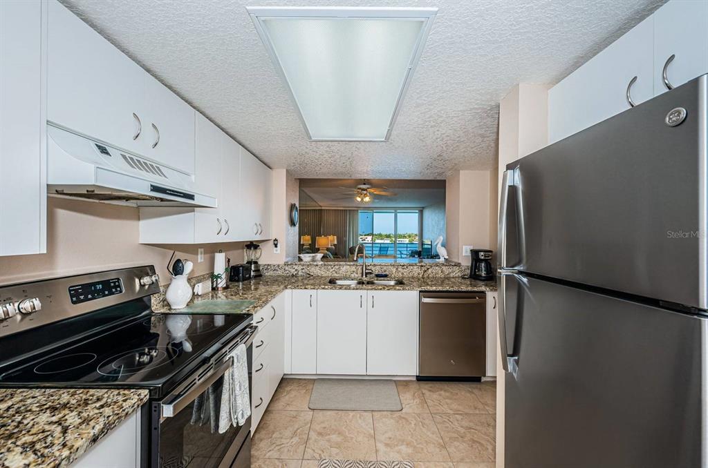 A kitchen with white cabinets, granite countertops, stainless steel appliances, and a view of water — 6093 BAHIA DEL MAR CIRCLE UNIT 478, ST PETERSBURG, FL