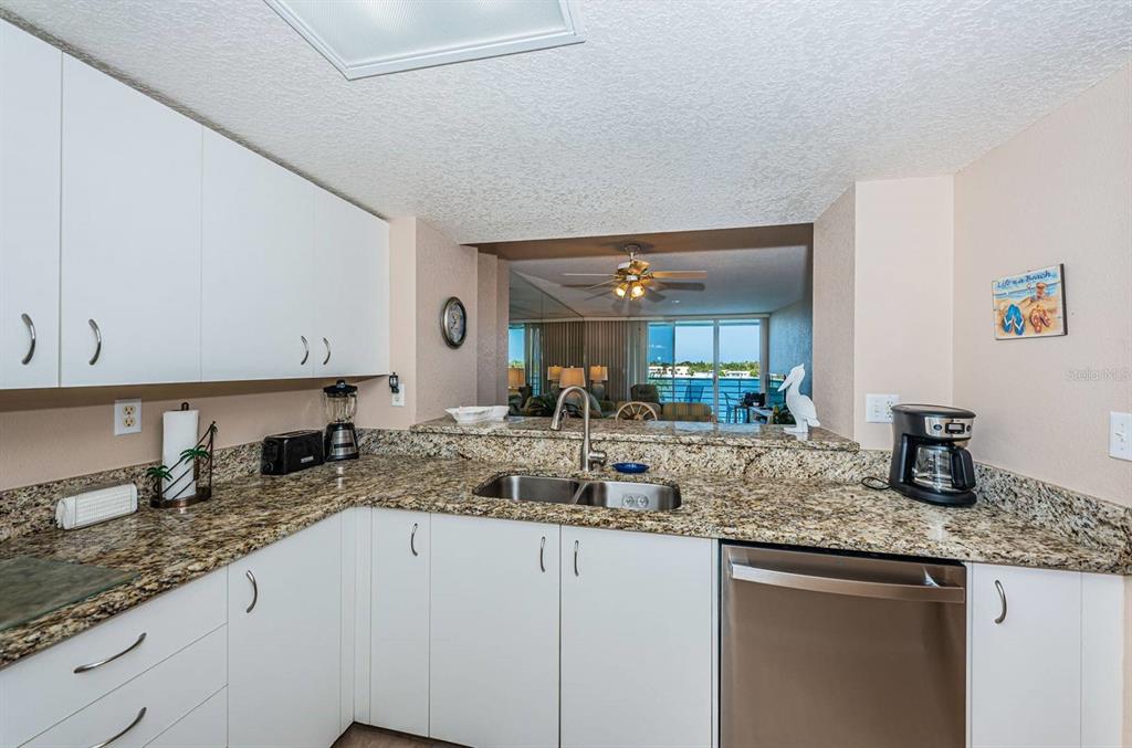 A kitchen with white cabinets, granite countertops, and a view through to a living area — 6093 BAHIA DEL MAR CIRCLE UNIT 478, ST PETERSBURG, FL