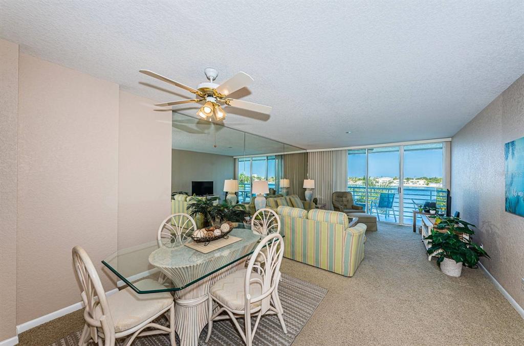 A dining area with a glass table and chairs opens into a living room with water views — 6093 BAHIA DEL MAR CIRCLE UNIT 478, ST PETERSBURG, FL