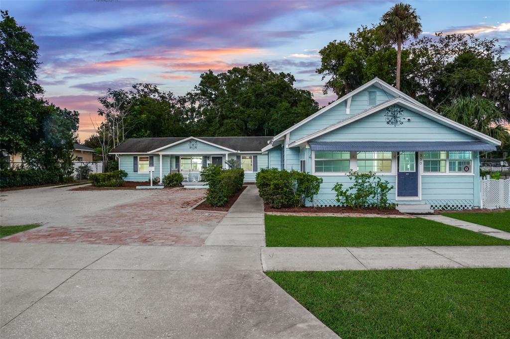 A light blue single-story house with a brick driveway and a concrete walkway — 330 S HIGHLAND STREET, MOUNT DORA, FL