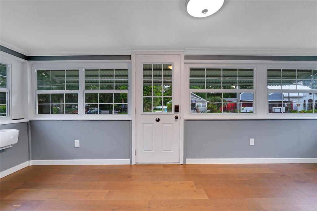 A sunroom with gray walls, wood-look flooring, and a central white door with windows — 330 S HIGHLAND STREET, MOUNT DORA, FL