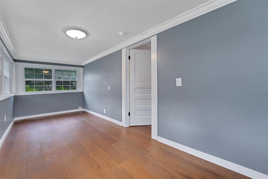 A room with gray walls, hardwood floors, a white door, and a multi-pane window — 330 S HIGHLAND STREET, MOUNT DORA, FL