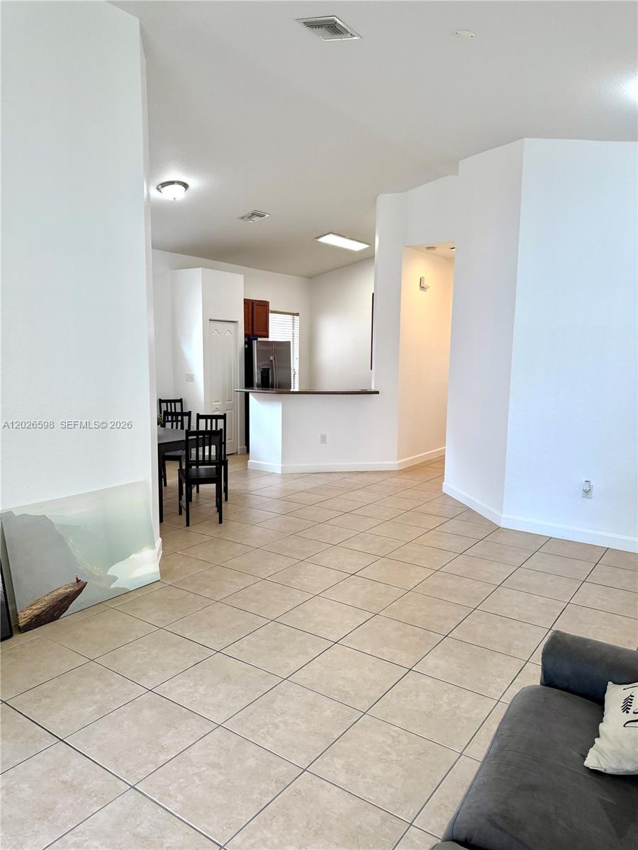 A tiled living area opens to a kitchen with a breakfast bar and dining space — 3951 NE 11th Dr, Homestead FL 33033, HOMESTEAD, FL