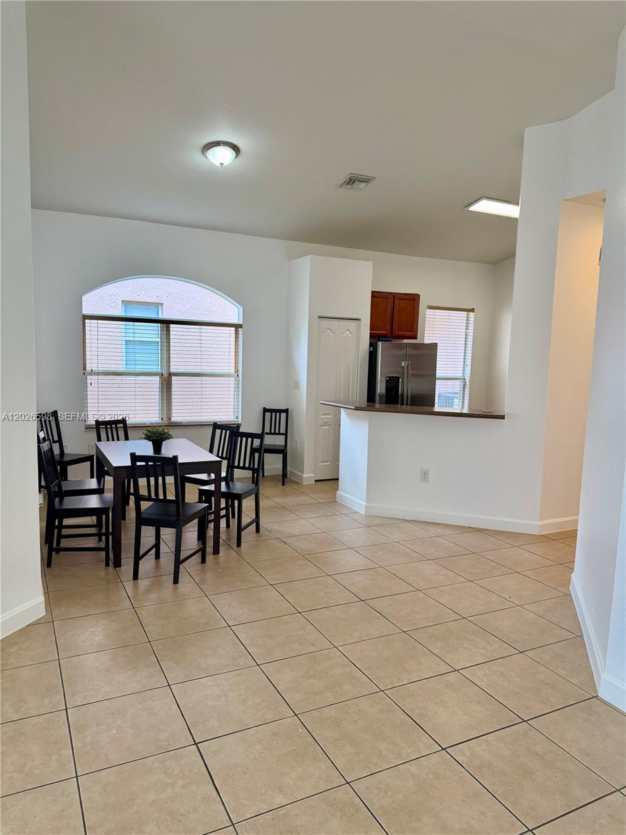 A dining area with tile floors sits adjacent to a kitchen featuring a breakfast bar — 3951 NE 11th Dr, Homestead FL 33033, HOMESTEAD, FL
