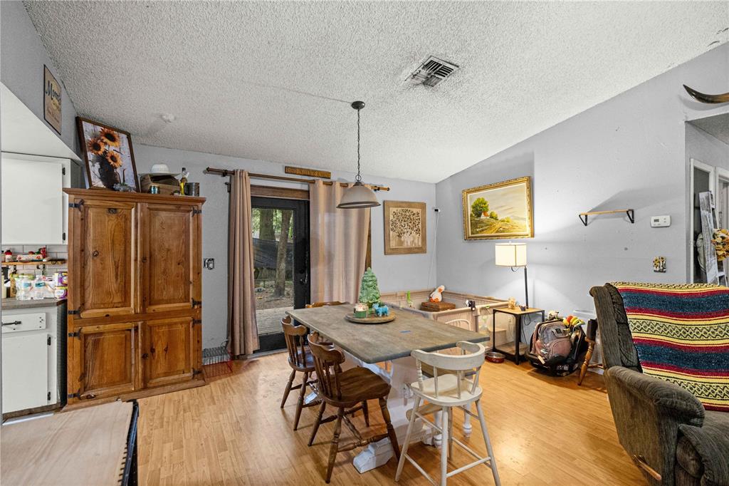 A dining area features a wooden table, chairs, a large armoire, and a sliding glass door — 3301 NE 23RD AVENUE, OCALA, FL