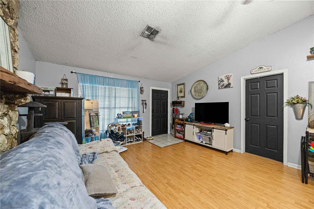 A living room features light wood flooring, gray walls, a stone fireplace, and two black doors — 3301 NE 23RD AVENUE, OCALA, FL