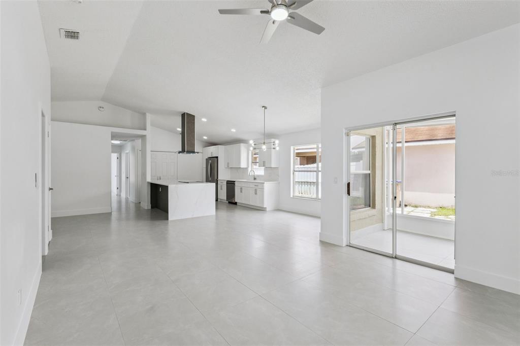 An open-concept kitchen and living area features white cabinetry, a kitchen island, and tile flooring — 2625 WALDEN COURT, KISSIMMEE, FL