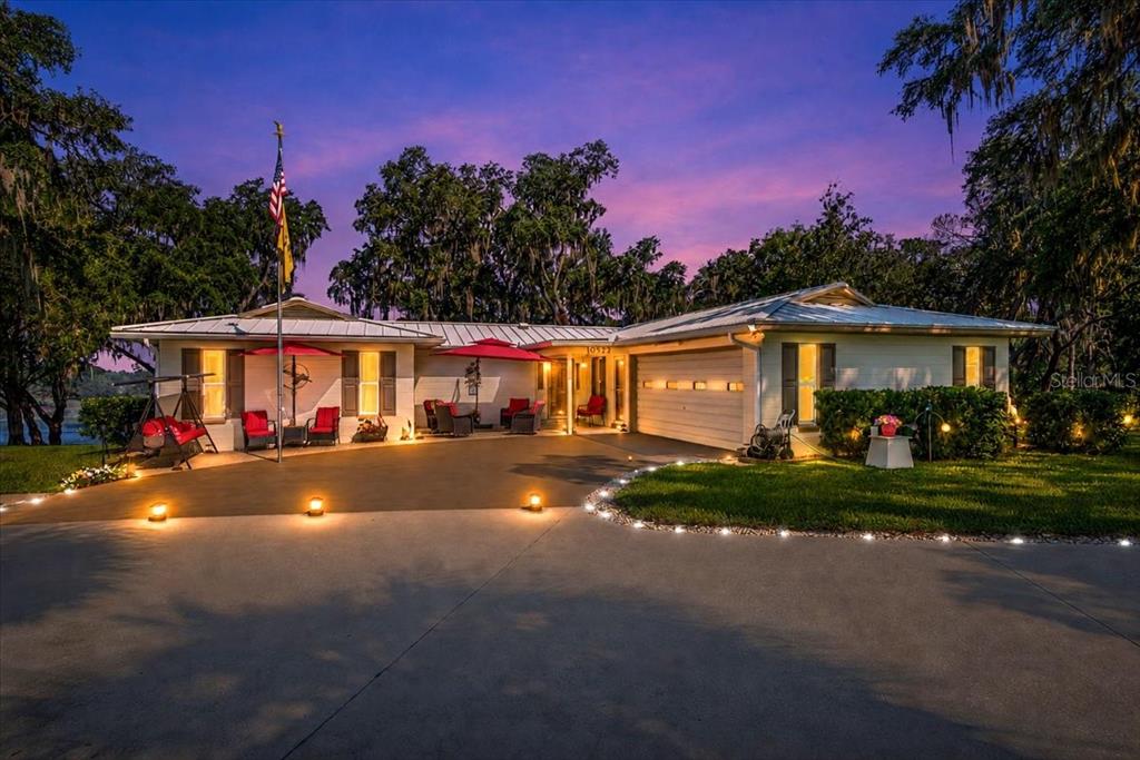 A single-story house with a metal roof and a paved driveway at twilight — 10522 SE 146TH TERRACE ROAD, OCKLAWAHA, FL