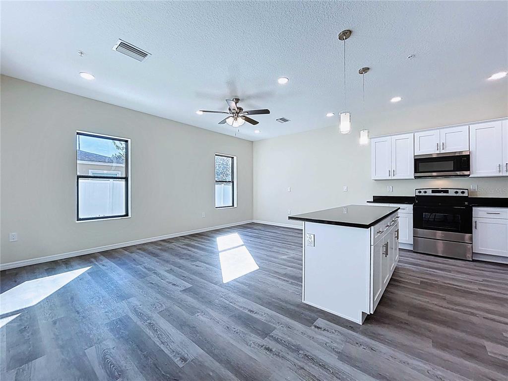 A kitchen with white cabinets and a black island opens into a living area — 4368 CAMBIO GARDENS COURT, TAMPA, FL