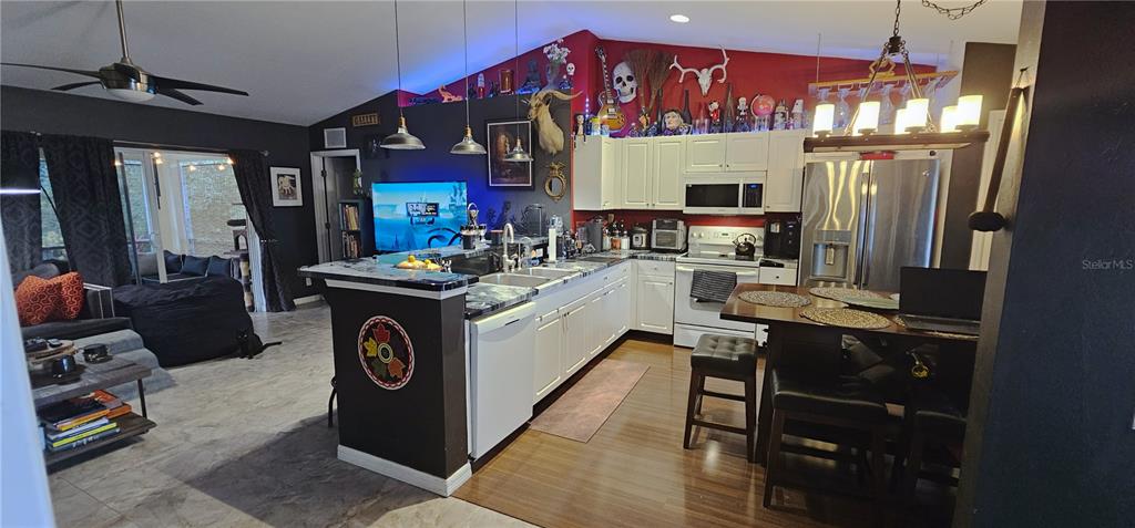 An open-concept kitchen and living area features white cabinetry, dark walls, and a breakfast bar — 720 BRANNEN AVENUE, LEHIGH ACRES, FL