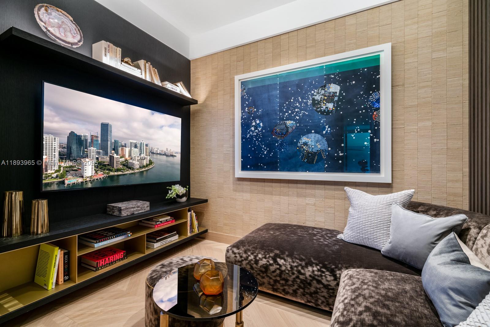 A modern living room features a wall-mounted television, built-in shelving, and a large abstract painting — 300 N Biscayne Blvd # 7803, Miami FL 33132, MIAMI, FL