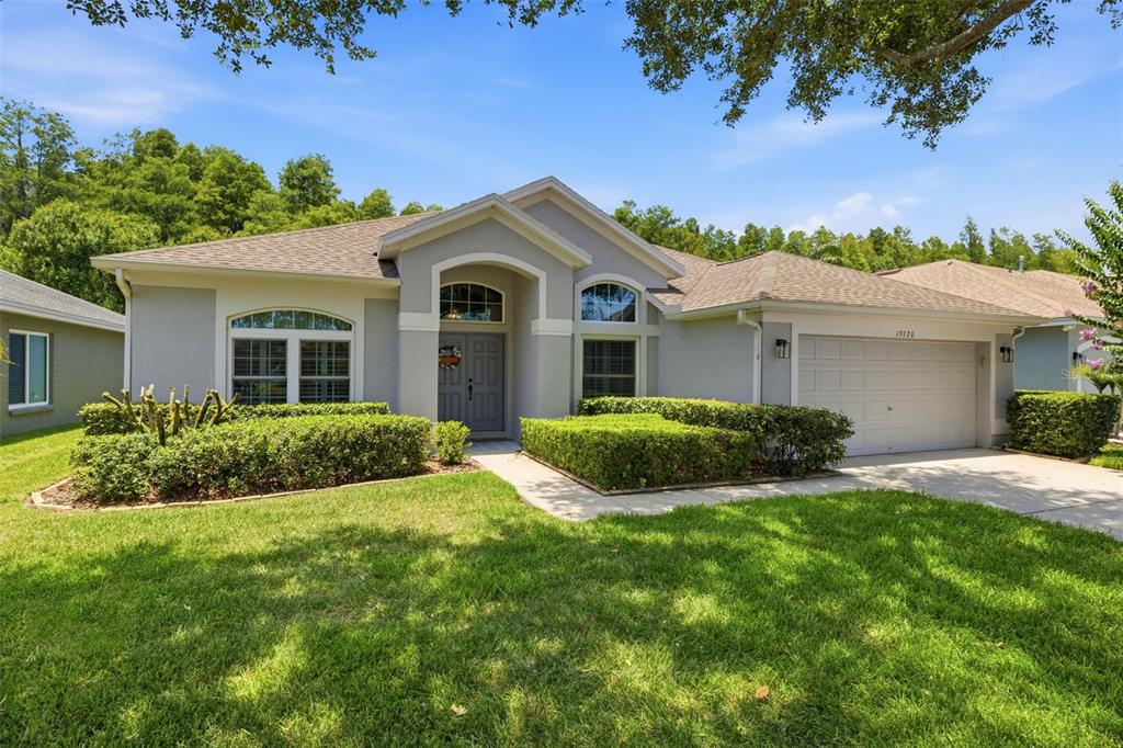 A single-story house with a gray exterior, arched windows, and a two-car garage — 19720 MORDEN BLUSH DRIVE, LUTZ, FL