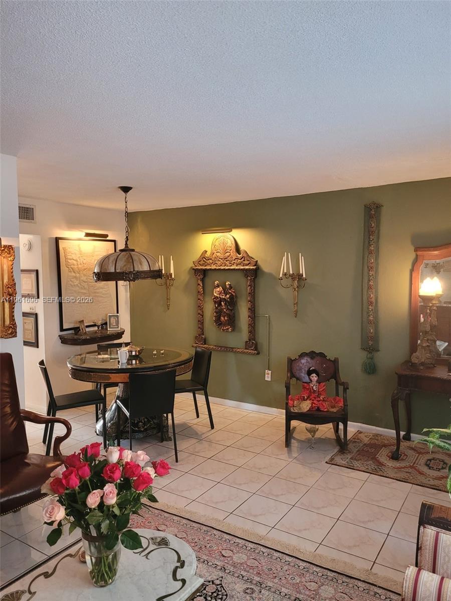 A dining area features a round table, green walls, ornate wall decor, and tiled flooring — 3881 W Flagler St # 208, Miami FL 33134, MIAMI, FL
