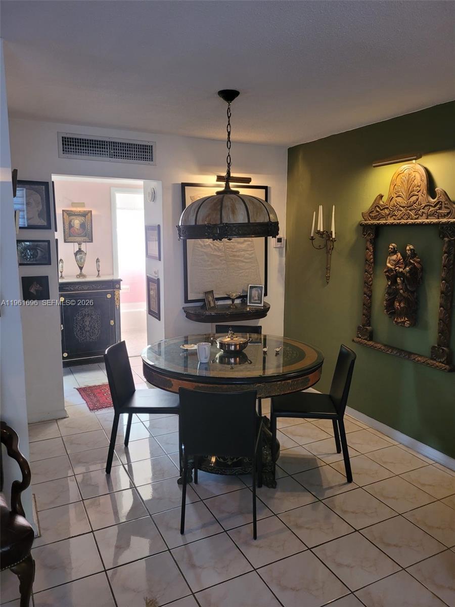 A dining area features a round glass table, black chairs, and decorative wall art — 3881 W Flagler St # 208, Miami FL 33134, MIAMI, FL