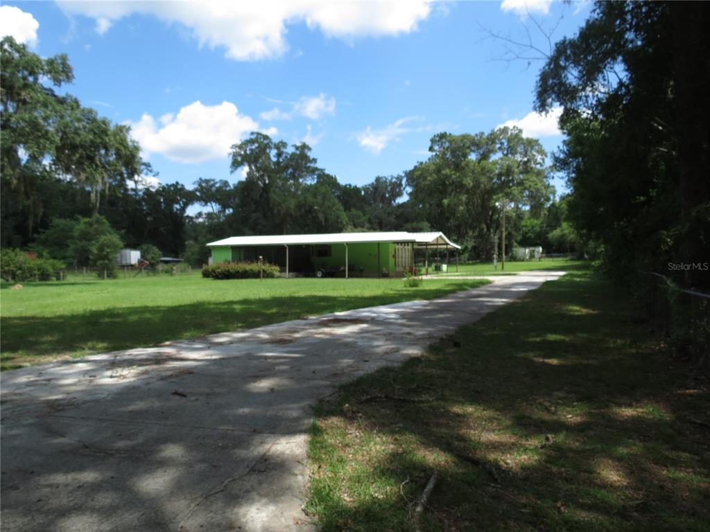 A bright green house with a large covered porch sits at the end of a driveway — 8545 S MAGNOLIA AVENUE, OCALA, FL