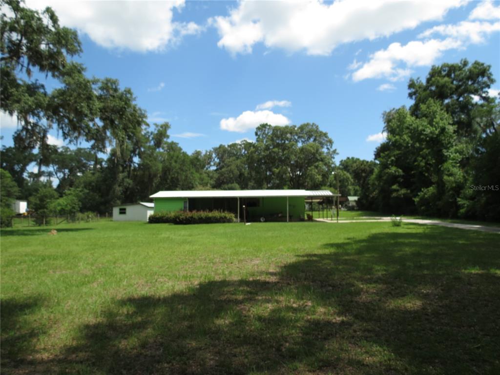 A bright green house with a large covered porch sits on a grassy lot — 8545 S MAGNOLIA AVENUE, OCALA, FL