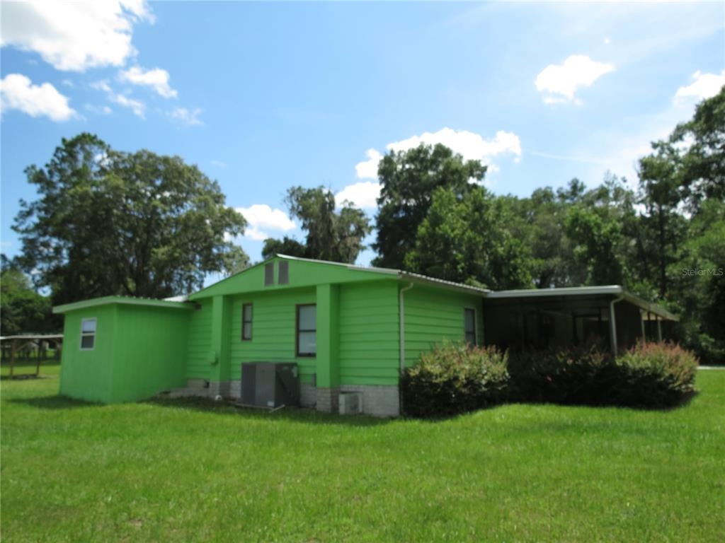 A bright green single-story house with a metal roof and a side screened-in porch — 8545 S MAGNOLIA AVENUE, OCALA, FL