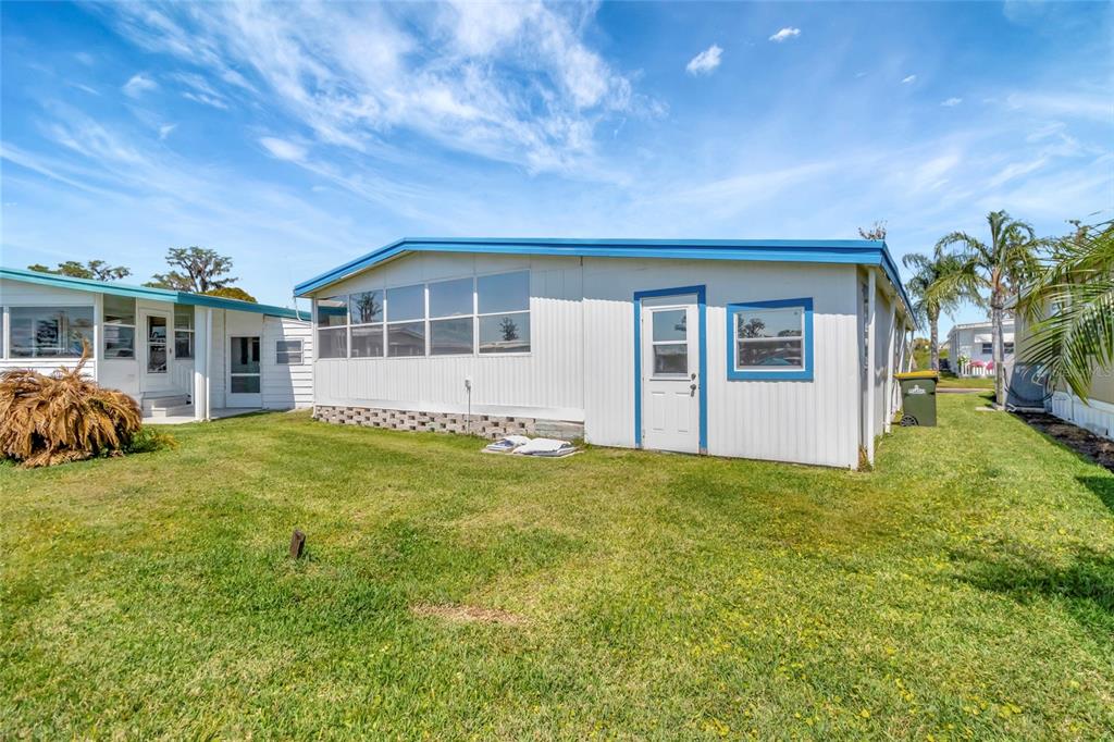 The exterior of a white mobile home features blue trim, a screen room, and grass — 1401 W HIGHWAY 50 UNIT 143, CLERMONT, FL