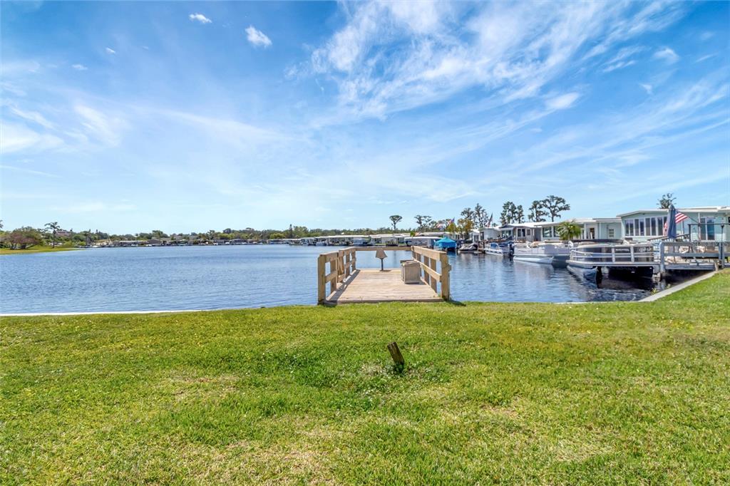 A wooden dock extends into a lake with several boats moored nearby under a blue sky — 1401 W HIGHWAY 50 UNIT 143, CLERMONT, FL