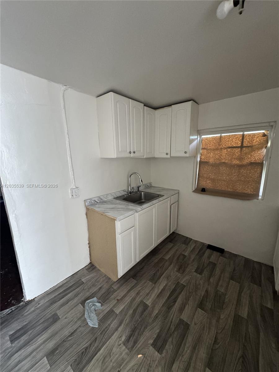 A small kitchen features white cabinets, a stainless steel sink, and wood-look laminate flooring — 2125 W 5th Ave, Hialeah FL 33010, HIALEAH, FL