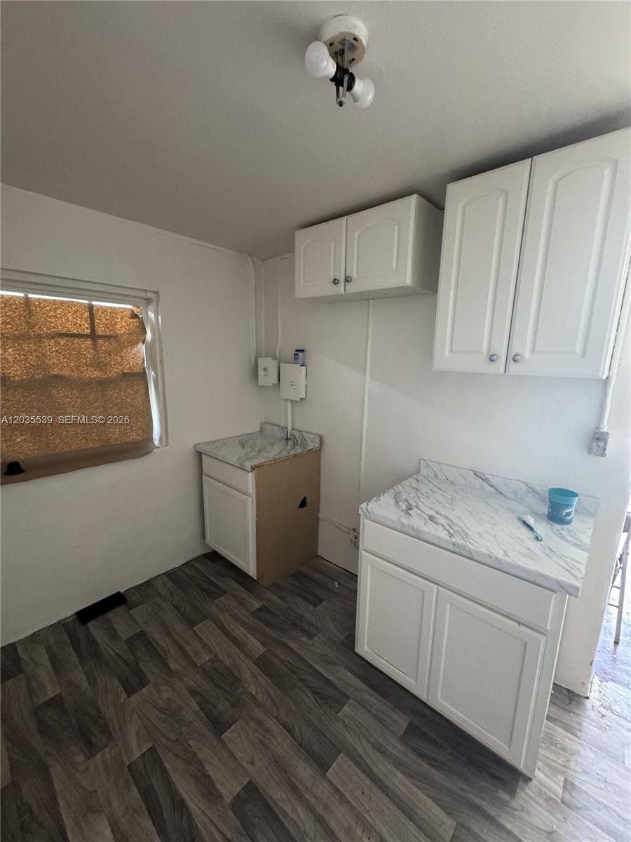 A small kitchen features white cabinets, marble-patterned countertops, and gray wood-look flooring — 2125 W 5th Ave, Hialeah FL 33010, HIALEAH, FL