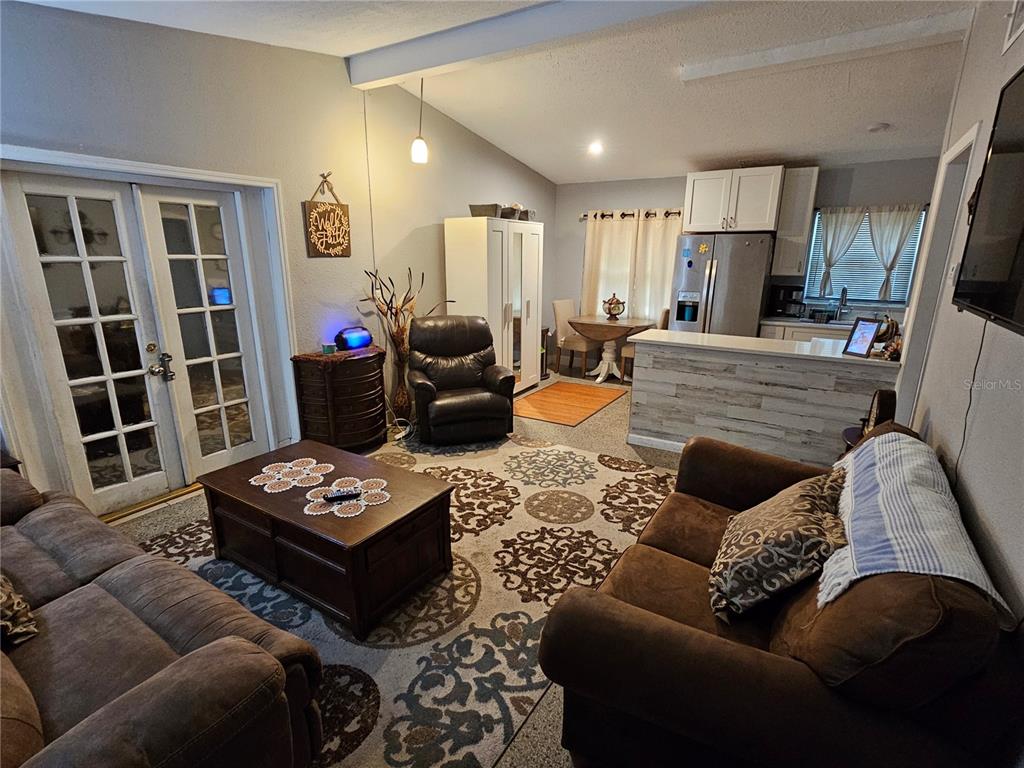 A living room with brown furniture and a patterned rug opens into a kitchen area — 730 SEMINOLA BOULEVARD, CASSELBERRY, FL