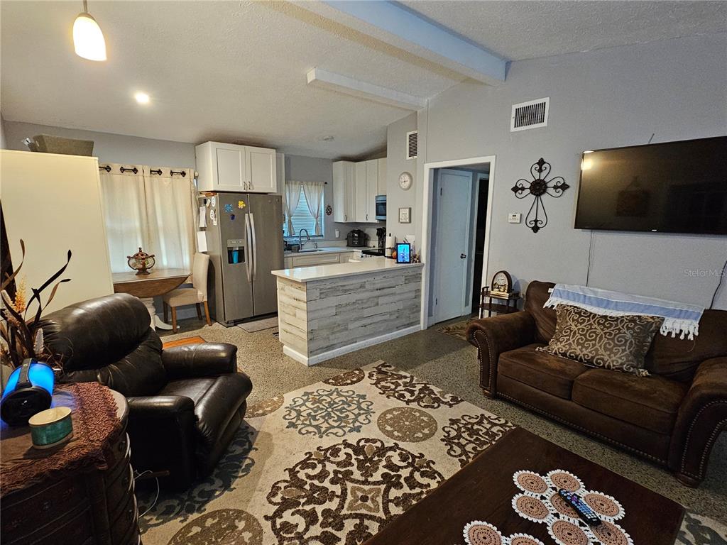 An open-concept living room and kitchen featuring a brown sofa, recliner, and breakfast bar — 730 SEMINOLA BOULEVARD, CASSELBERRY, FL