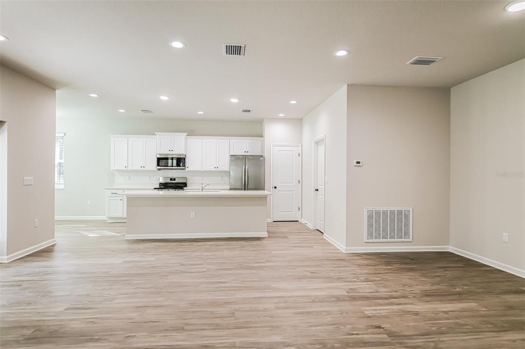 A kitchen with white cabinets, stainless steel appliances, and an island overlooks a living area — 20 GREENTREE STREET, HOMOSASSA, FL