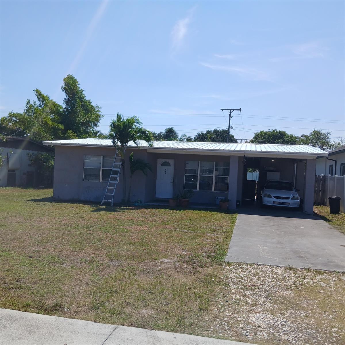 A single-story house with a metal roof, a front lawn, and a carport with a car — 811 S Broadway, Lantana FL 33462, LANTANA, FL