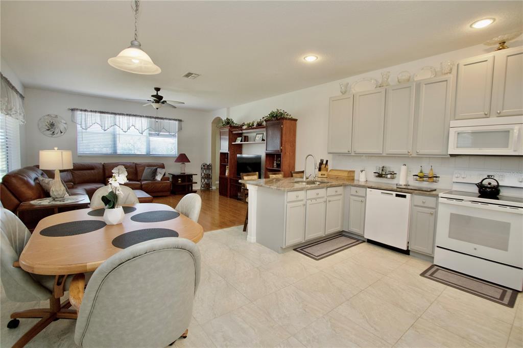 An open-concept kitchen with light gray cabinets and a dining area next to a living room — 11205 EDGE PARK DRIVE, HUDSON, FL
