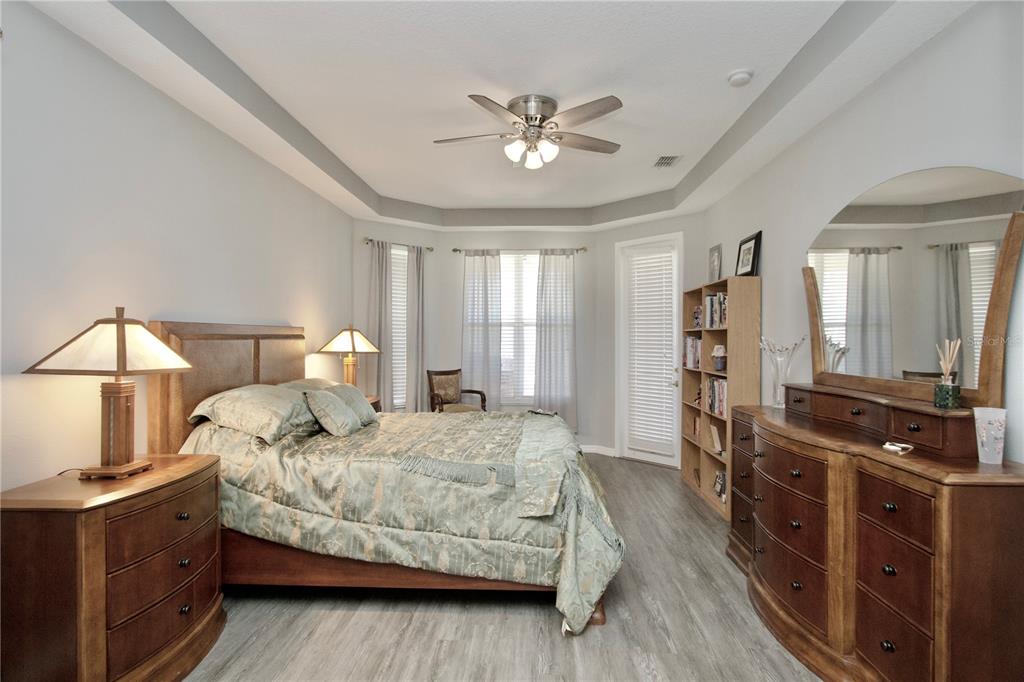 A bedroom features a bed, two wooden dressers, a bookshelf, and a ceiling fan — 11205 EDGE PARK DRIVE, HUDSON, FL